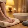 Pieds reposant sur une serviette près d'une bassine d'eau chaude fumante, ambiance rituel du soir