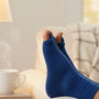 Personne détendue sur un canapé, chaussettes séparateurs d'orteils bleu royal, réveil et tisane à côté
